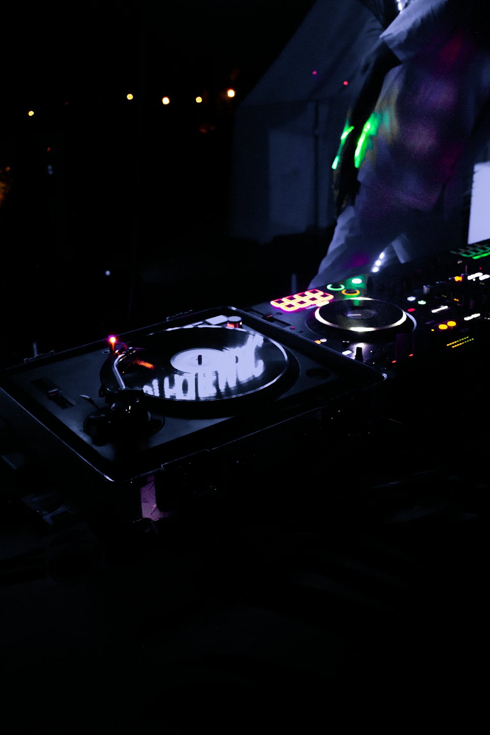 DJ mixant de la musique sur des tables tournantes avec des éclairages colorés.