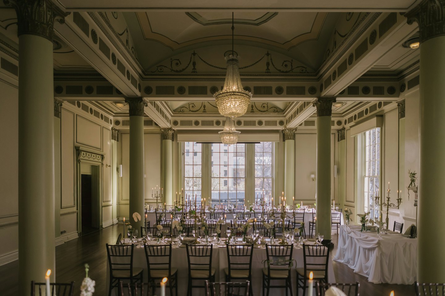 Élégante salle de bal aménagée avec des tables éclairées à la bougie et des arrangements floraux.